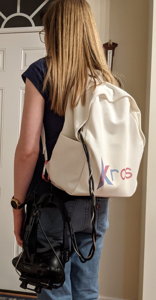 Closed backpack with Kros logo and a head mounted display latched on.